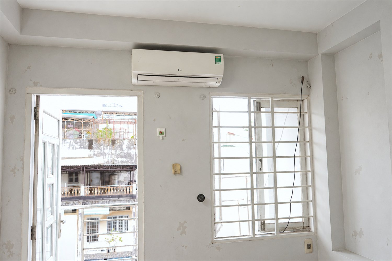 Cũng căn phòng đó lúc chưa sơn — tường xám cũ, loang lổ